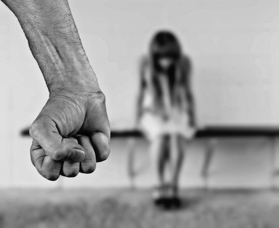 Faust von einem Mann. Im Hintergrund eine traurige junge Frau